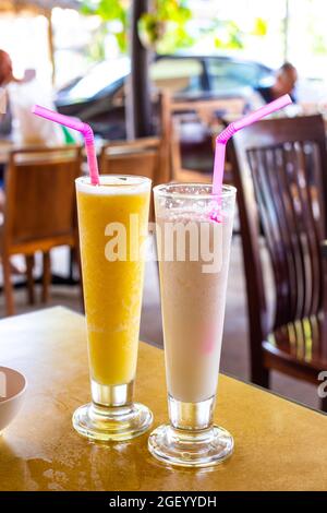 Zwei Hälse reife Früchte Mango und Kokosnuss auf einem Tisch in einem Café Stockfoto