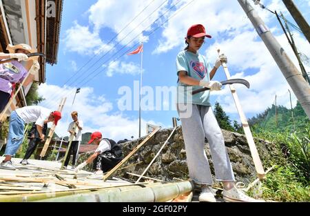 (210822) -- RONGSHUI, 22. August 2021 (Xinhua) -- am 21. August 2021 machen Studenten Bambuszäune im Dorf Wuying, das an der Grenze zwischen der Autonomen Region Guangxi Zhuang im Süden Chinas und der Provinz Guizhou im Südwesten Chinas liegt. Im Sommer 2021 führte ein ehrenamtliches Team aus Studenten und Mittelschülern lokale Schüler an verschiedenen Aktivitäten wie der Pflege von Setzlingen, dem Lernen über immaterielle Kulturgüter und dem Sammeln alter Bauernwerkzeuge für Museen Teil. (Xinhua/Huang Xiaobang) Stockfoto