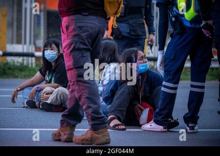 22. August 2021, Bangkok, Bangkok, Thailand: Junge Mädchen sitzen auf der Straße, nachdem sie von der Polizei verhaftet wurden. In der achten Nacht in Folge ist der Bezirk DIN Daeng in Bangkok Schauplatz heftiger Auseinandersetzungen. Informell in Abstimmung mit der prodemokratischen Protestbewegung, die im Juli 2020 begann, haben Berufsschülergruppen zunehmend Konfrontationen mit der Polizei, Frustriert mit den schrecklichen Auswirkungen der dritten Welle von Covid -19 hat auf Thailand und die governmentâ €™s wahrgenommen Inkompetenz bei der Bewältigung der Krise sehen diese Jugendlichen keine andere Option, als auf Gewalt gegen den Staat. (Cre Stockfoto