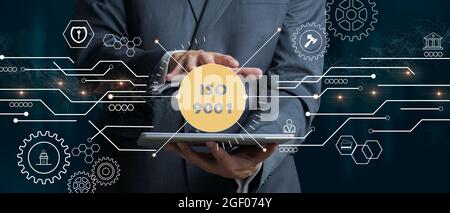 Geschäftsmann mit einem Tablet mit dem ISO 9001-Symbol. ISO-Normen Qualitätssicherung Gewährleistung Business Technologie Konzept. Gemischte Medien Stockfoto