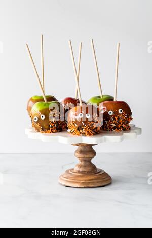 Karamelläpfel, die für Halloween auf einem Standfuß, vor einem hellen Hintergrund, dekoriert sind. Stockfoto