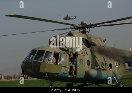 Ein US-amerikanischer UH-60 Blackhawk ist während einer Trainingsmission in Khanjarkhe, Provinz Parwan, Afghanistan, während der Crew-Chef auf einem Mi-17 Hubschrauber der afghanischen Sicherheitskräfte seine Kontrollen durchführt, bevor er während einer Trainingsmission von der Abholung von Kommandos abheben kann. Die ANSF-Kommandos nehmen an ihrer ersten Trainingsmission Teil, während sie an der ANSF Air Assault Academy im Bagram Airfield, Afghanistan, März 10, teilnehmen. Stockfoto