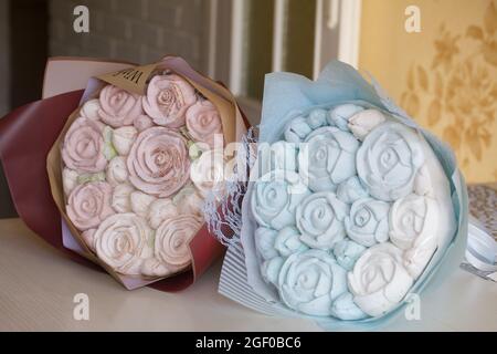 Marshallow Blumensträuße in handwerklicher Verpackung. Bestehen aus marmelallow Rosen und Tulpen. Die Blumensträuße liegen auf der Tischfläche. Stockfoto