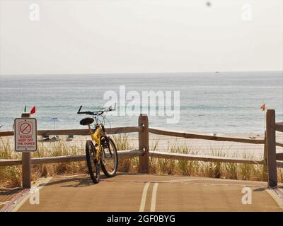 Gelbes Fahrrad, das sich in New Jersey in der Nähe des Ozeans an einen Holzzaun lehnt. Stockfoto