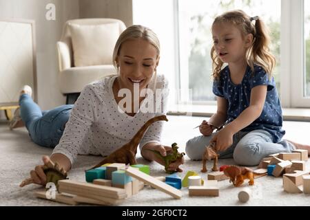 Glücklich positive Mutter und Kind spielen mit Dinosauriern Stockfoto