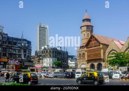 Mumbai, Maharashtra, Indien : Schwarz-gelbe Taxis fahren am Crawford-Marktgebäude vorbei, das 1869 im normannischen gotischen Stil erbaut wurde. Stockfoto