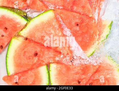 Melone close-up in Flüssigkeit mit Blasen. Slicec der roten reifen Melone in Wasser. Nahaufnahme von frischen Scheiben roter Melone auf weißem Hintergrund Stockfoto