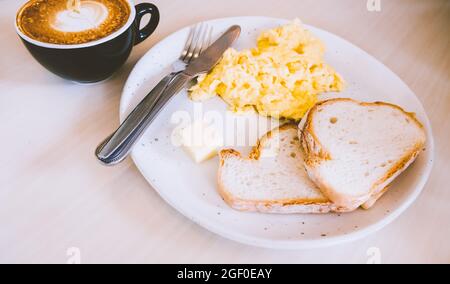 Mascarpone Rühreier mit Knoblauch Toast mit heißem Kaffee Latte Essen Frühstück Mahlzeit. Stockfoto