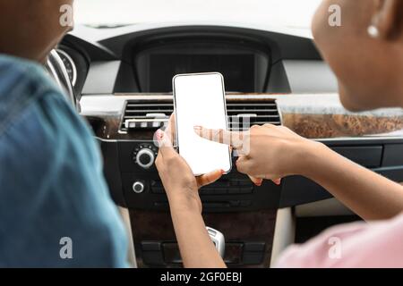 Schwarzer Mann und Frau, die im Auto ein Mobiltelefon benutzen, Mockup Stockfoto