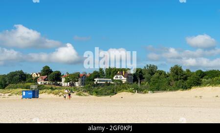 Öffentlicher Sandstrand im Dorf Yantarny, Region Königsberg, Russland. Im Sommer verlassen ein Mann und eine Frau die Ostsee. Stockfoto