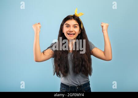 Emotional Indian teen girl gesturing JA mit beiden Händen auf blauen Studio-Hintergrund Stockfoto