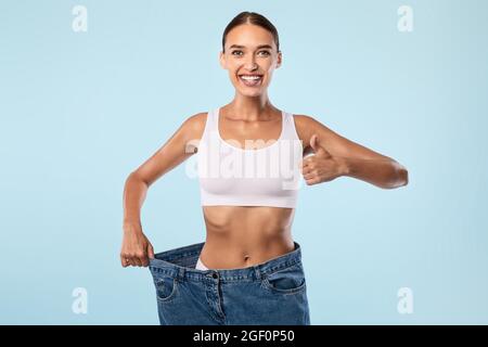 Frau Zieht Ihre Alte Große Lose Jeans Zeigt Daumen Nach Oben Stockfoto