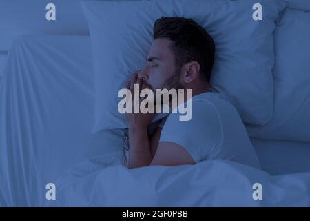 Gesundes Schlafen, Schlafhygienekonzept. Junger Mann schläft zu Hause im bequemen Bett, Kopierplatz, Draufsicht Stockfoto