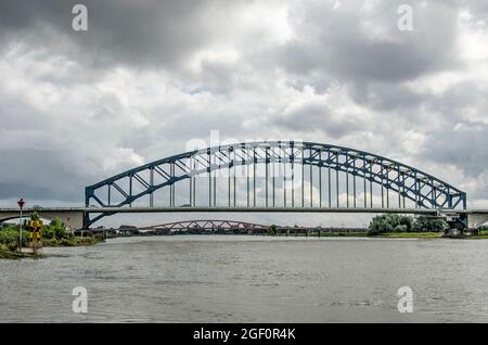 Zwolle, Niederlande, 10. August 2021: Blick entlang der IJssel mit der historischen Bogenbrücke und vor ihr die neue Hanzeboog-Brücke, unter einer d Stockfoto