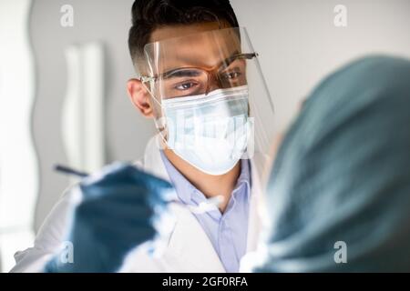 Nahaufnahme eines arabischen männlichen Zahnärztes, der die Zähne muslimischer weiblicher Patienten begeht Stockfoto