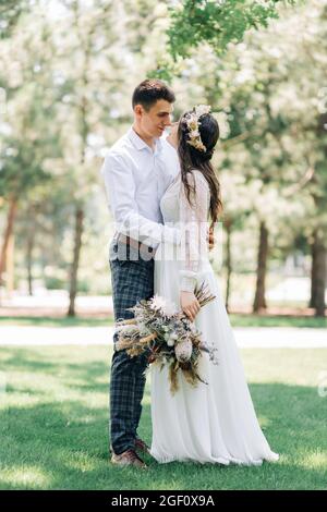 Schönes Brautpaar, schöner Bräutigam und Braut in weißem Hochzeitskleid, Brautpaar lachen und küssen, im Park, Konzept der Liebe und Glück, weddi Stockfoto