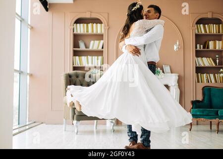 Glückliches Brautpaar, attraktive Braut und Bräutigam umarmen sich, der Bräutigam umarmt und hält die Braut in seinen Armen und umkreist sie, Happy Wedding day, Th Stockfoto