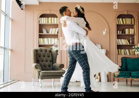 Glückliches Brautpaar, attraktive Braut und Bräutigam umarmen sich, der Bräutigam umarmt und hält die Braut in seinen Armen und umkreist sie, Happy Wedding day, Th Stockfoto