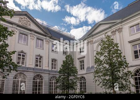 Gent, Flandern, Belgien - 30. Juli 2021: Weißes palaziales Gebäude und Innenhof der Kunstakademie unter blauer Wolkenlandschaft mit etwas grünem Laub. Stockfoto