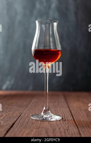Grappa-Glas mit Brandy oder Sherry oder Calvados auf Holztisch. Stockfoto