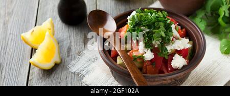 Frischer Salat aus gebackenen Paprika, Tomaten, Zwiebeln, Gurken, Petersilie, Dill und Fetakäse in einer Keramikschale. Traditionelle serbische Küche. Selektive Stockfoto