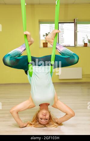 Ein junges Mädchen praktiziert Yoga auf einer Hängematte im Flur. Das Mädchen führt Asanas in Limbo. Stockfoto