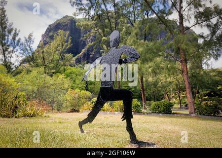 Mauritius, Mascarene-Inseln. Metallskulptur eines entweichenden Sklaven. Das Denkmal der Sklavenstraße am Fuße des Berges Le Morne Brabant. Der Berg wa Stockfoto