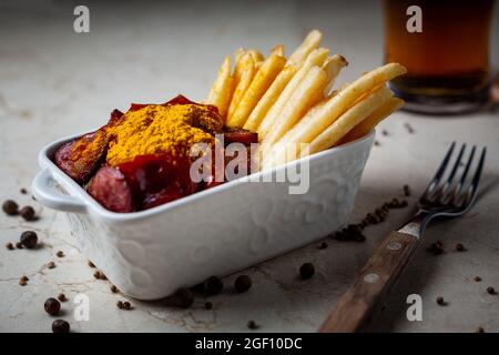 Currywurst mit pommes in weißer Schüssel auf Marmortisch. Stockfoto