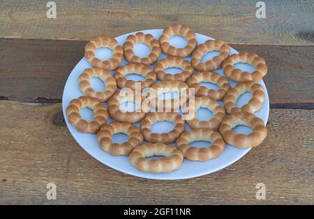 Einige leckere Bagels auf einem weißen Teller auf einem Holzhintergrund Stockfoto