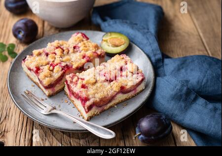 Saftige Pflaumenkuchen-Scheiben mit knuspriger Streusel-Belag auf rustikalem Holzhintergrund Stockfoto