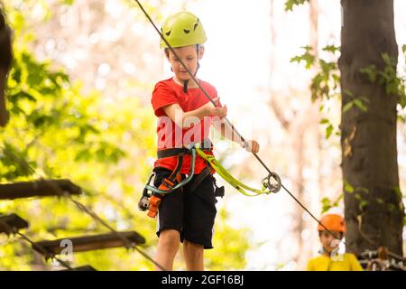 Niedliche Schuljunge genießen einen sonnigen Tag in einen Kletterpark Abenteuer Aktivität Stockfoto