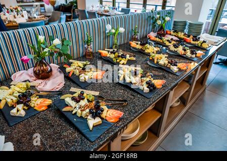 Die schwarzen Teller mit verschiedenen leckeren Käse und Obst auf der Theke Stockfoto