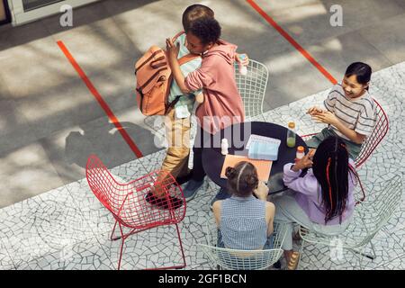 Blick aus der Höhe auf eine multiethnische Gruppe von Kindern, die sich während des Mittagessens in der modernen Schule am Tisch im Freien treffen, Platz zum Kopieren Stockfoto