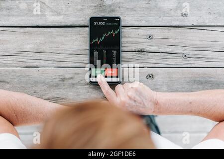 Anlegerin nutzt die Handy-App für Investitionen, um Kryptowährungen zu kaufen Stockfoto