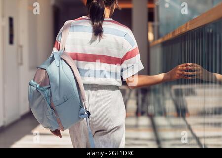 Rückansicht Aufnahme eines jungen Schulmädchen, das Rucksack hält, während es im Sonnenlicht zur Klasse geht, Platz kopieren Stockfoto