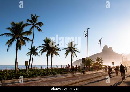 RIO DE JANEIRO, BRASILIEN - 27. MÄRZ 2016: Die Menschen laufen bei Sonnenuntergang auf der autofreien Avenida Vieira Souto am Strand von Ipanema entlang. Stockfoto