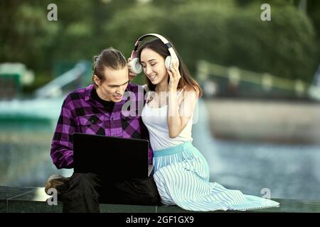 Junge Paare mit Laptop haben sich im Sommer im Freien datieren lassen. Stockfoto