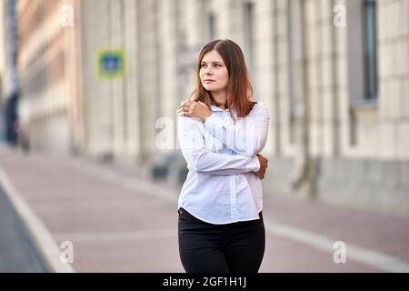 Frau mit braunen Haaren im Hemd steht auf der Straße. Stockfoto
