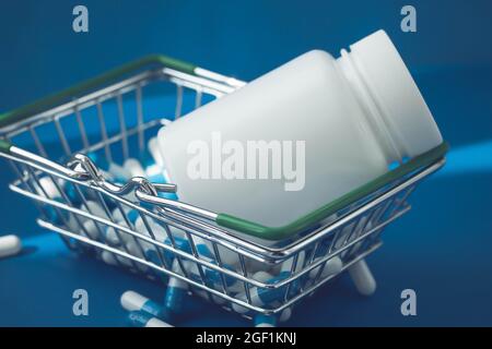 Pillen in einem Lebensmittelkorb. Medikamentenkapseln auf dem Tisch. Käufer in der Apotheke. Medikamente online bestellen. Pillen auf blauem Hintergrund in einer Schachtel. Stockfoto