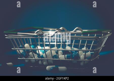 Pillen in einem Lebensmittelkorb. Medikamentenkapseln auf dem Tisch. Käufer in der Apotheke. Medikamente online bestellen. Pillen auf blauem Hintergrund in einer Schachtel. Stockfoto