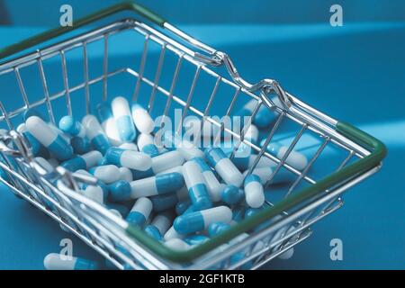 Pillen in einem Lebensmittelkorb. Medikamentenkapseln auf dem Tisch. Käufer in der Apotheke. Medikamente online bestellen. Pillen auf blauem Hintergrund in einer Schachtel. Stockfoto