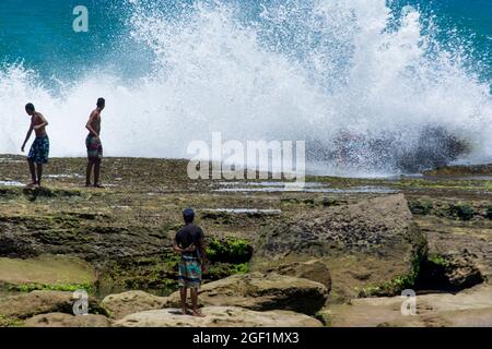 Salvador, Bahia, Brasilien - 17. Oktober 2015: Menschen riskieren ihr Leben auf Felsen mit starken Wellen. Stockfoto