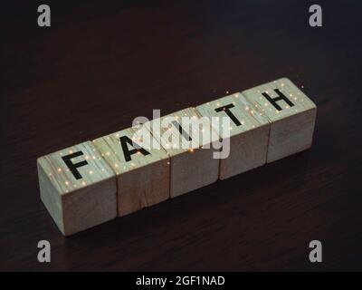 Faith, Worte auf Holzwürfelblöcken auf dunkelbraunem Holzhintergrund, Nahaufnahme. Stockfoto