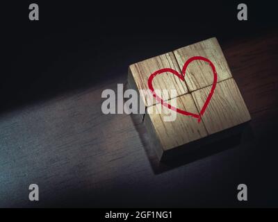 Rotes Herz auf Holzwürfelblöcken auf dunkelbraunem Holzhintergrund. Stockfoto