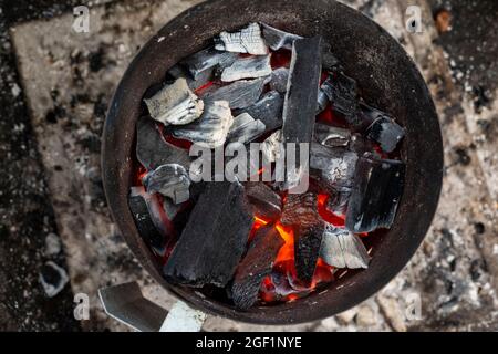 Holzklumpenkohle schwelt in einem Kamin, bevor sie zum Grill verwendet wird. Stockfoto