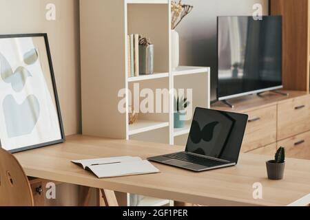 Hintergrundbild von minimalem Home Office-Setup mit leerem Laptop auf Holzschreibtisch in gemütlicher Wohnung, Kopierplatz Stockfoto