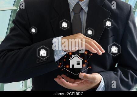 Geschäftsmann Haus auf der Hand virtuellen Bildschirm Hologramm. Kauf, Verkauf und Vermietung von Häusern oder Immobilien-Konzept.Home oder Immobilien-Versicherung Stockfoto