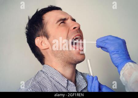 Doctor Doing Coronavirus Test für männlichen Patienten. Entnahme einer Speichelprobe von einem Mann. DNA-Test. Sammlung von Schleim aus dem Hals für die Forschung in der l Stockfoto