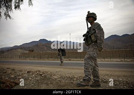 US Army Staff Sgt. Mike Cruz und ein afghanischer Grenzpatrouillensoldat sorgen im Rahmen einer Spatenstich-Zeremonie für den Ghulam Mohammad Sports Complex am 12. Dezember 2009 für Sicherheit außerhalb der Vorwärtsoperation Base Joyce, Afghanistan. Cruz ist der nicht beauftragte Offizier, der für die persönliche Sicherheitsabteilung, das Hauptquartier und die Kompanie des Hauptquartiers, das 1. Bataillon, das 32. Infanterie-Regiment, das 3. Brigade-Kampfteam, die 10. Bergdivision verantwortlich ist. Stockfoto