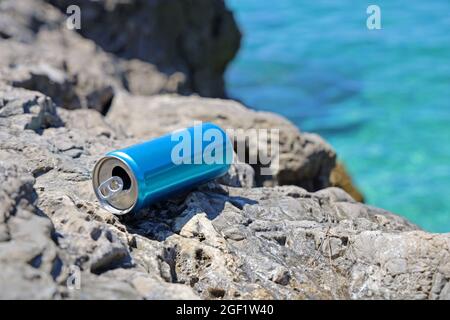 Blaues Aluminium-Getränk kann an der Steinküste am Mittelmeer zurückgelassen werden, Problem der Meeresverschmutzung Stockfoto